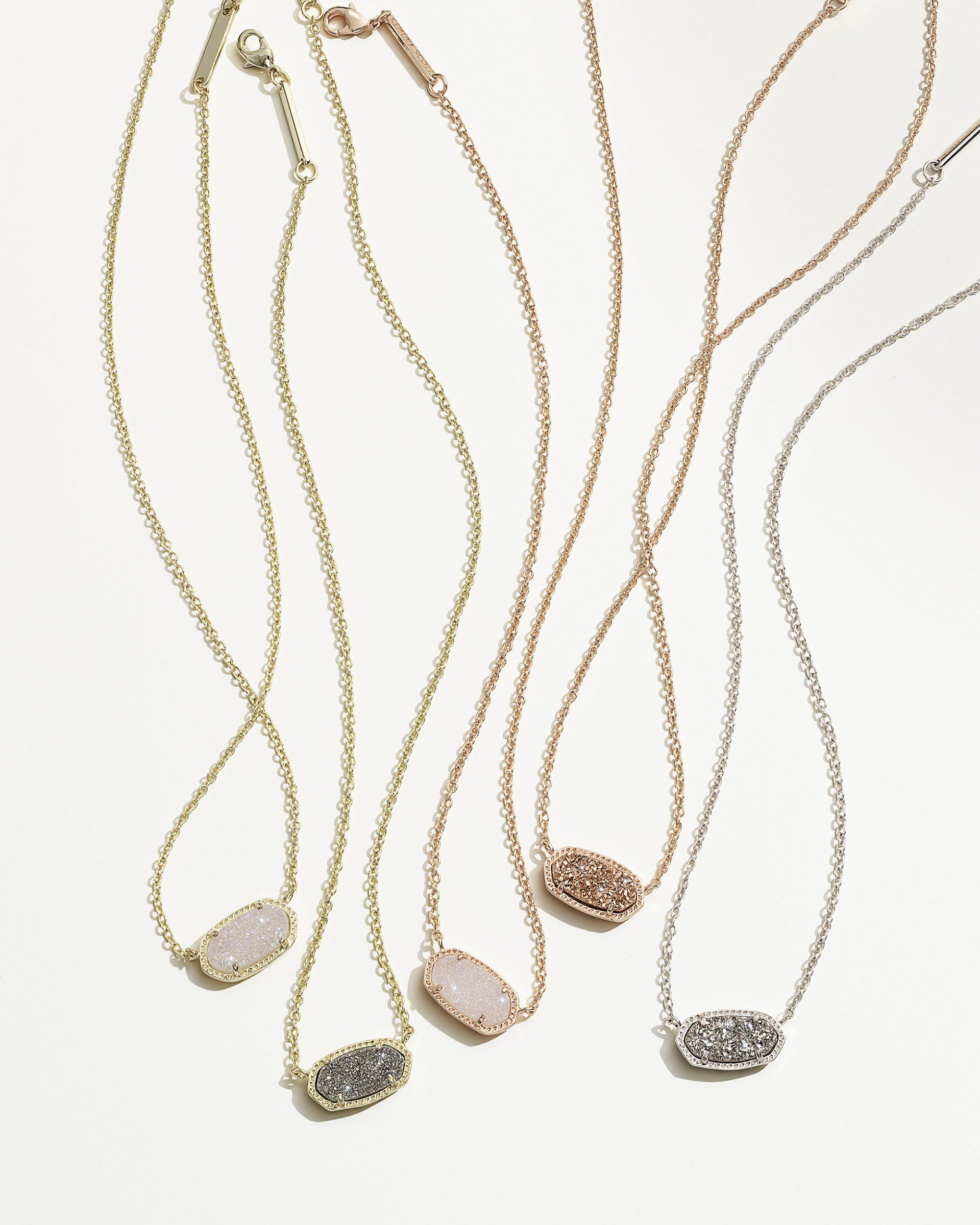 Gold, rose gold, and silver necklaces with oval gemstone pendants on white background.