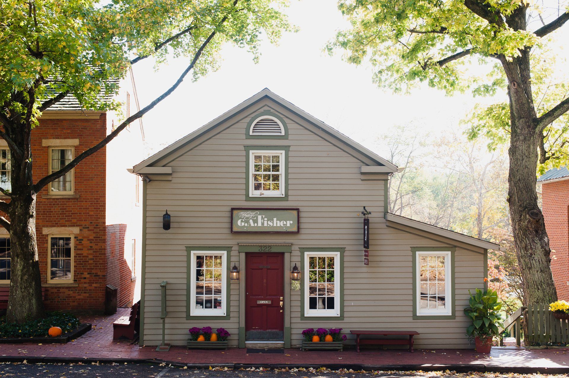 A gray, clapboard building with a red door,