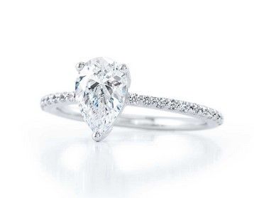 Pear-shaped diamond engagement ring with a pave band, set against a white background.