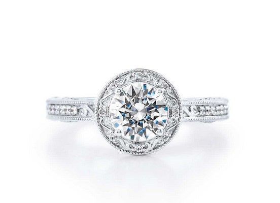 Diamond engagement ring with a round center stone and intricate halo setting.