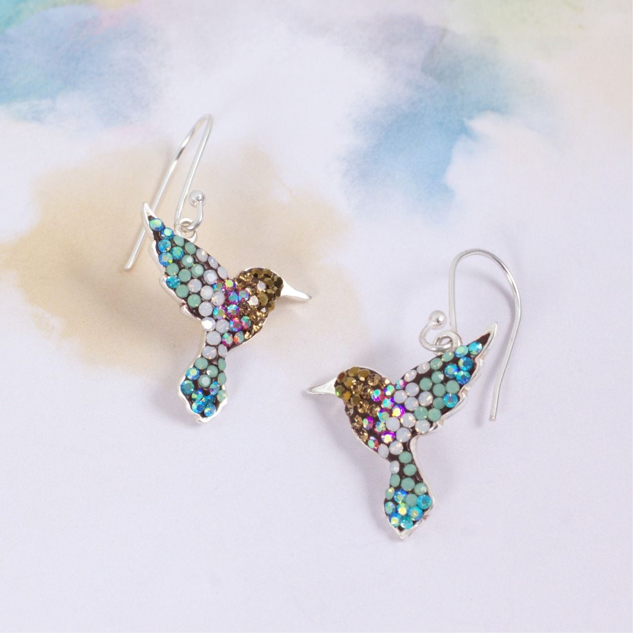 Hummingbird earrings with blue, teal, and brown gemstones on a light background.