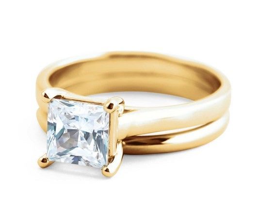 Gold engagement ring with square, light-colored gemstone. Matching band next to it.