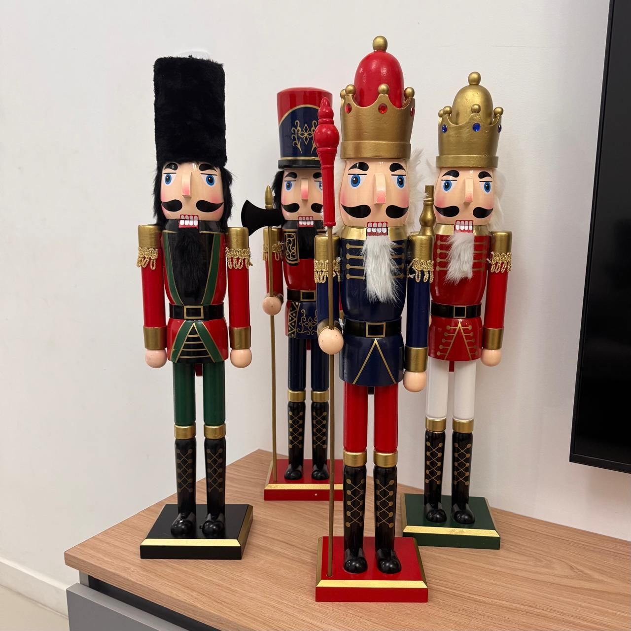 Cuatro cascanueces decorativos de madera se encuentran sobre una superficie de madera.
