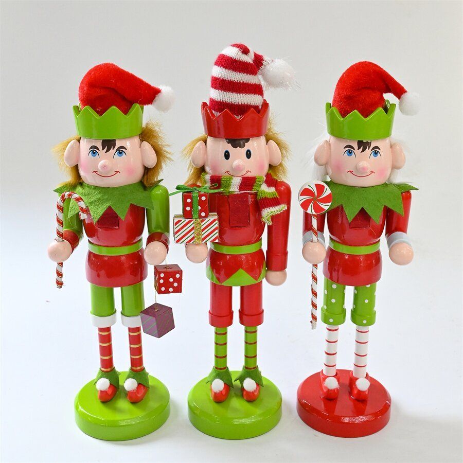 Tres elfos navideños cascanueces con trajes rojos y verdes, sosteniendo bastones de caramelo y regalos.