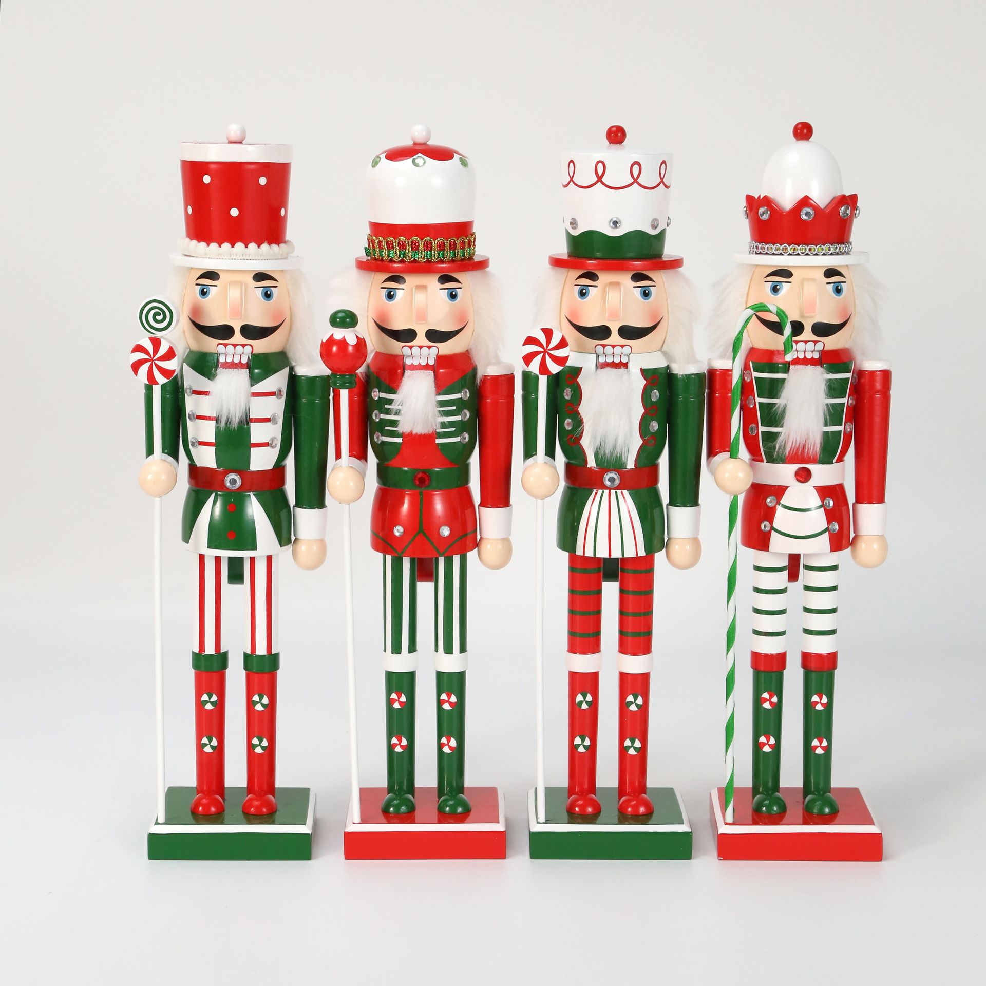 Cuatro figuras de cascanueces de madera con uniformes y sombreros rojos y verdes, sosteniendo bastones de caramelo.