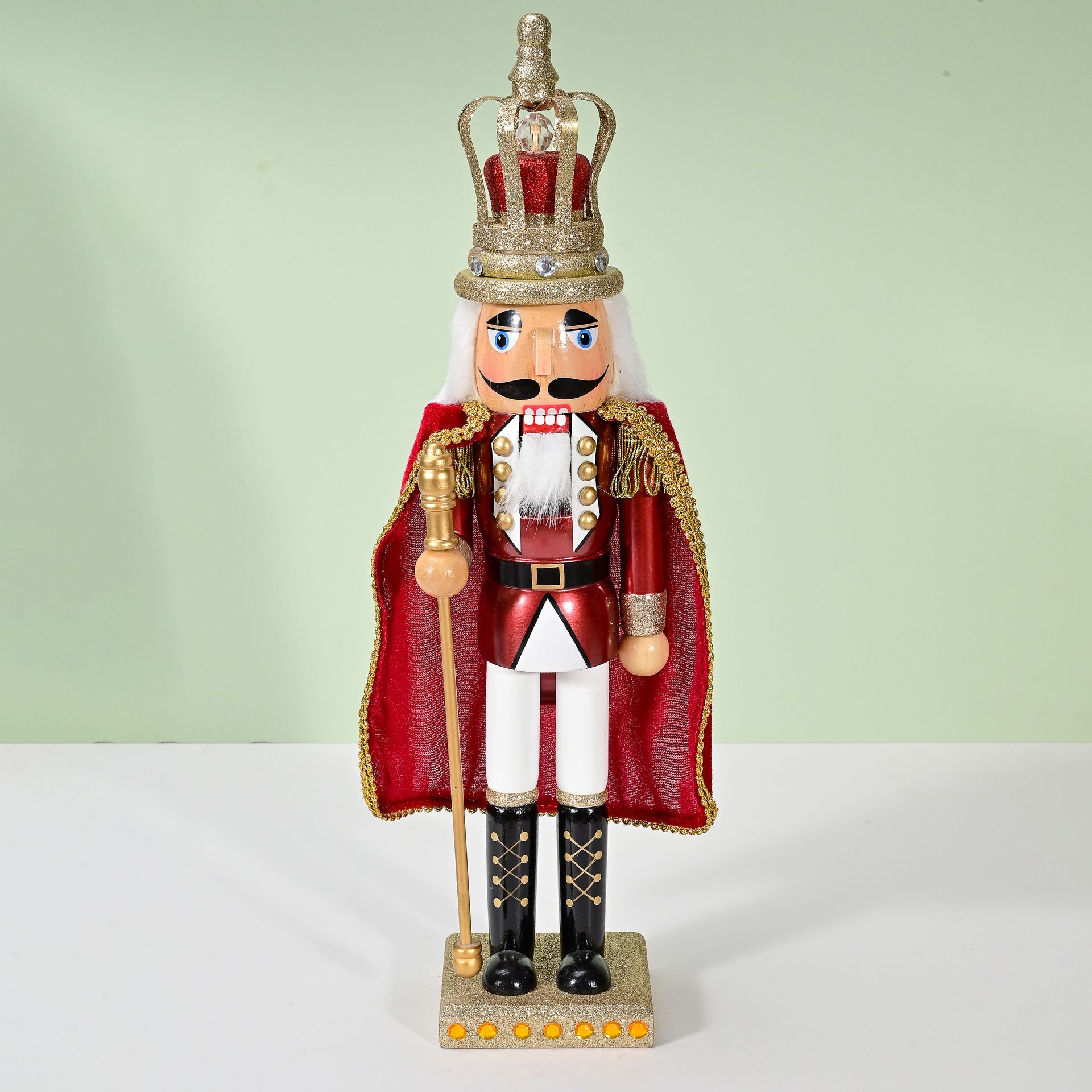 Figura de cascanueces, capa roja y dorada, corona, sosteniendo bastón.