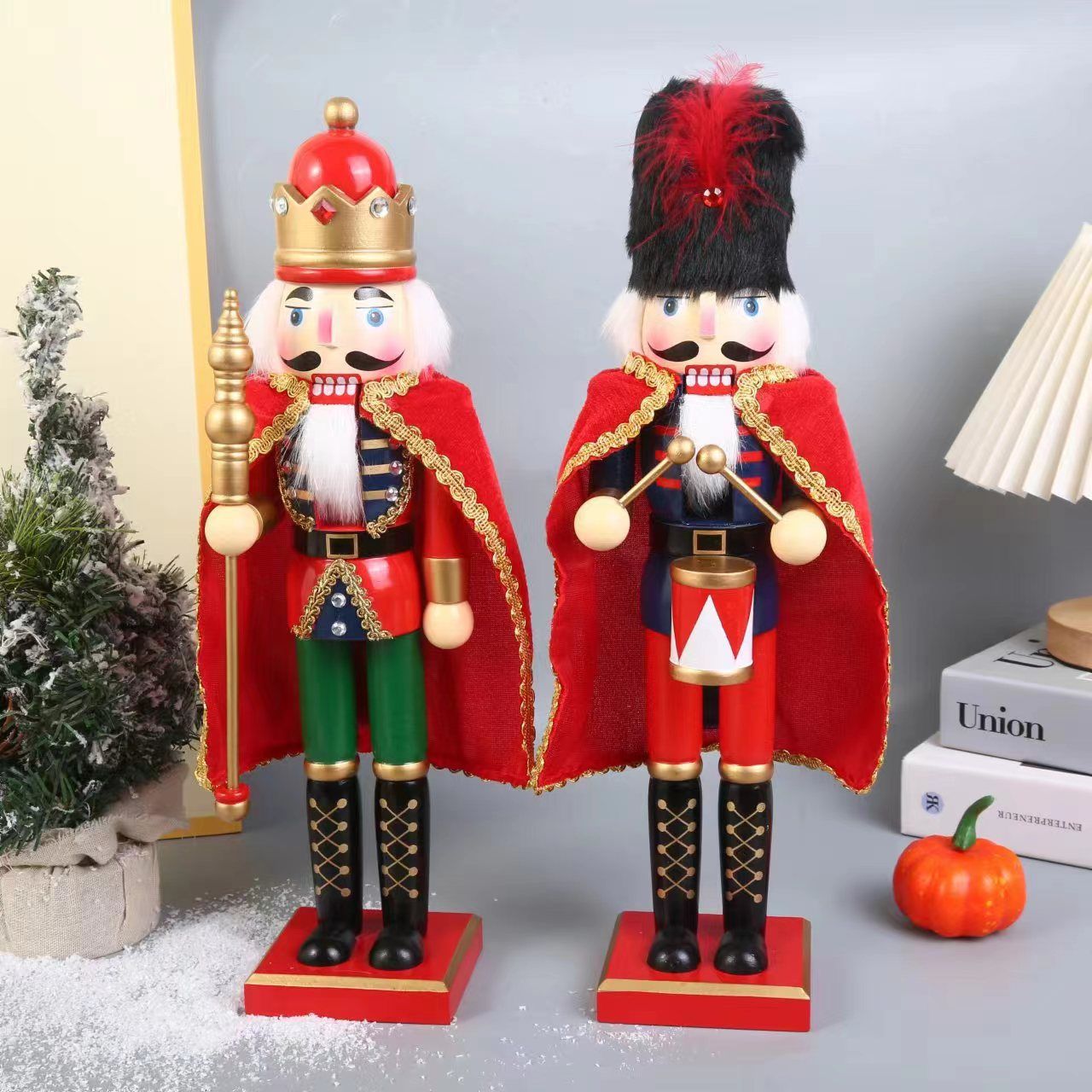 Dos cascanueces de madera con capas rojas, uno sosteniendo un bastón y el otro un tambor.