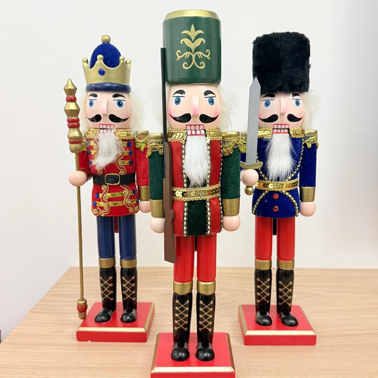 Tres cascanueces de madera de colores sobre una mesa: un rey, un soldado y un guardia.