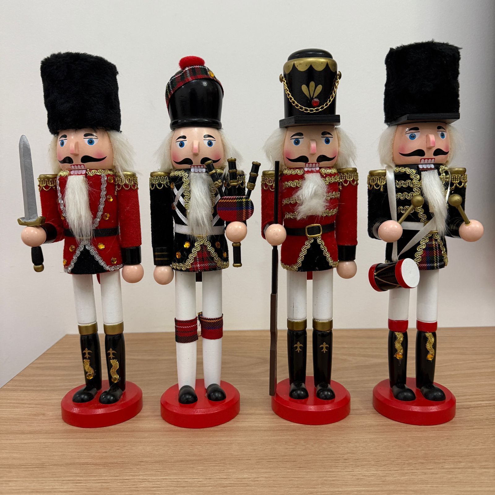 Cuatro cascanueces de juguete con uniformes de soldados sobre una mesa de madera.