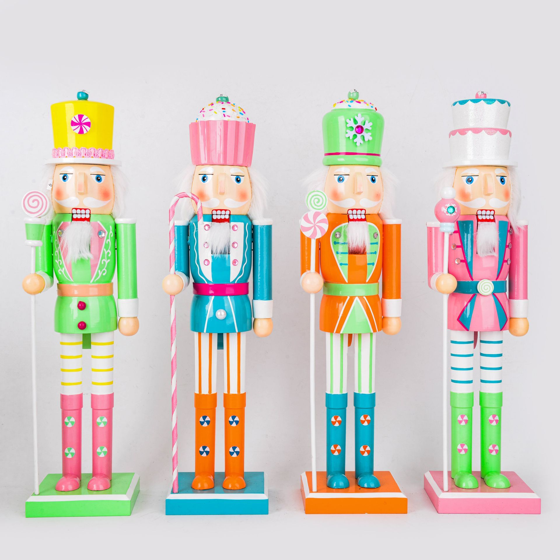 Cuatro coloridas figuras de cascanueces con varios sombreros y bastones de caramelo sobre un fondo blanco.