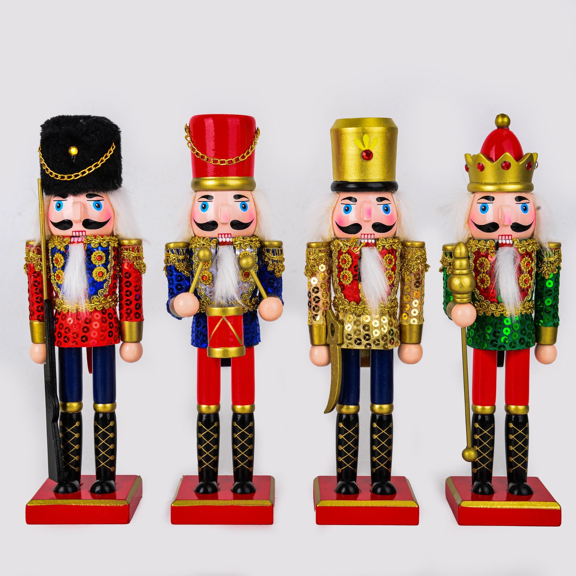 Cuatro cascanueces decorativos de madera con uniformes rojos, azules y dorados, colocados sobre bases rojas.