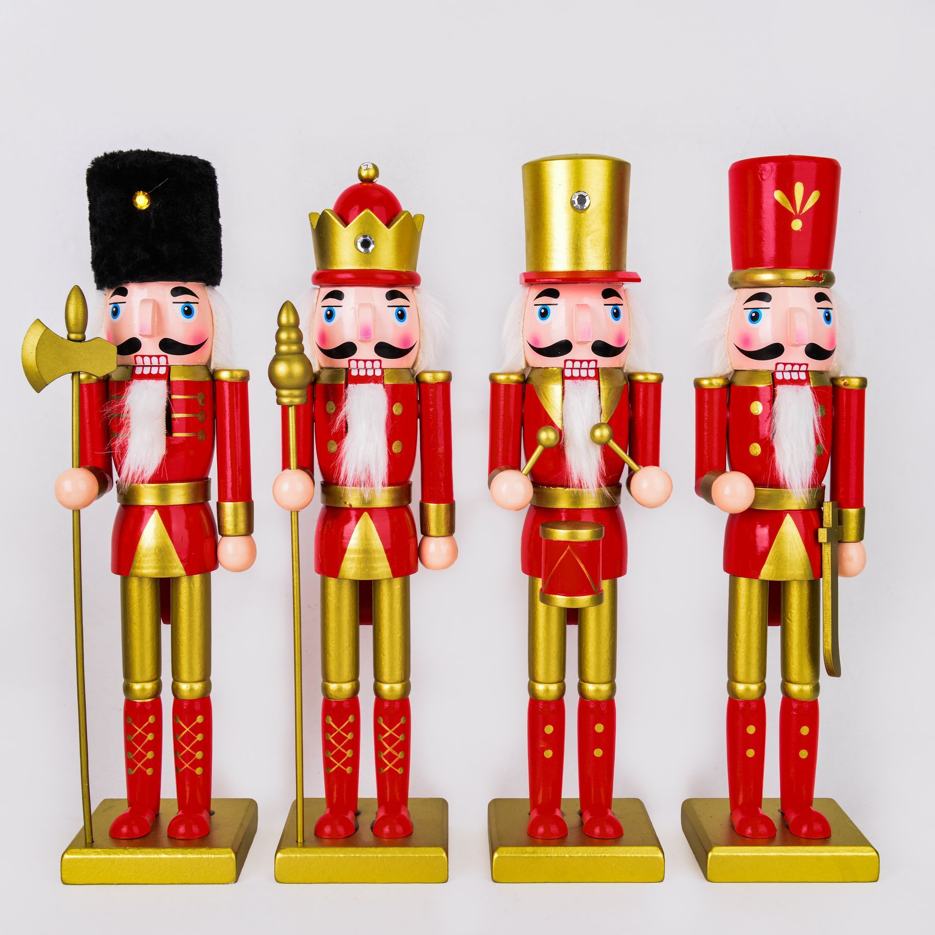 Cuatro soldados cascanueces rojos y dorados con diferentes sombreros y accesorios, de pie sobre bases doradas.