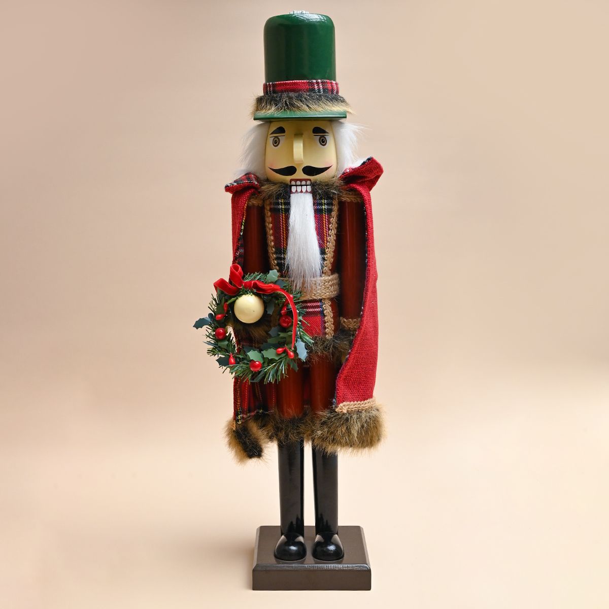 Figura de cascanueces con abrigo rojo y sombrero verde, sosteniendo una corona de flores.