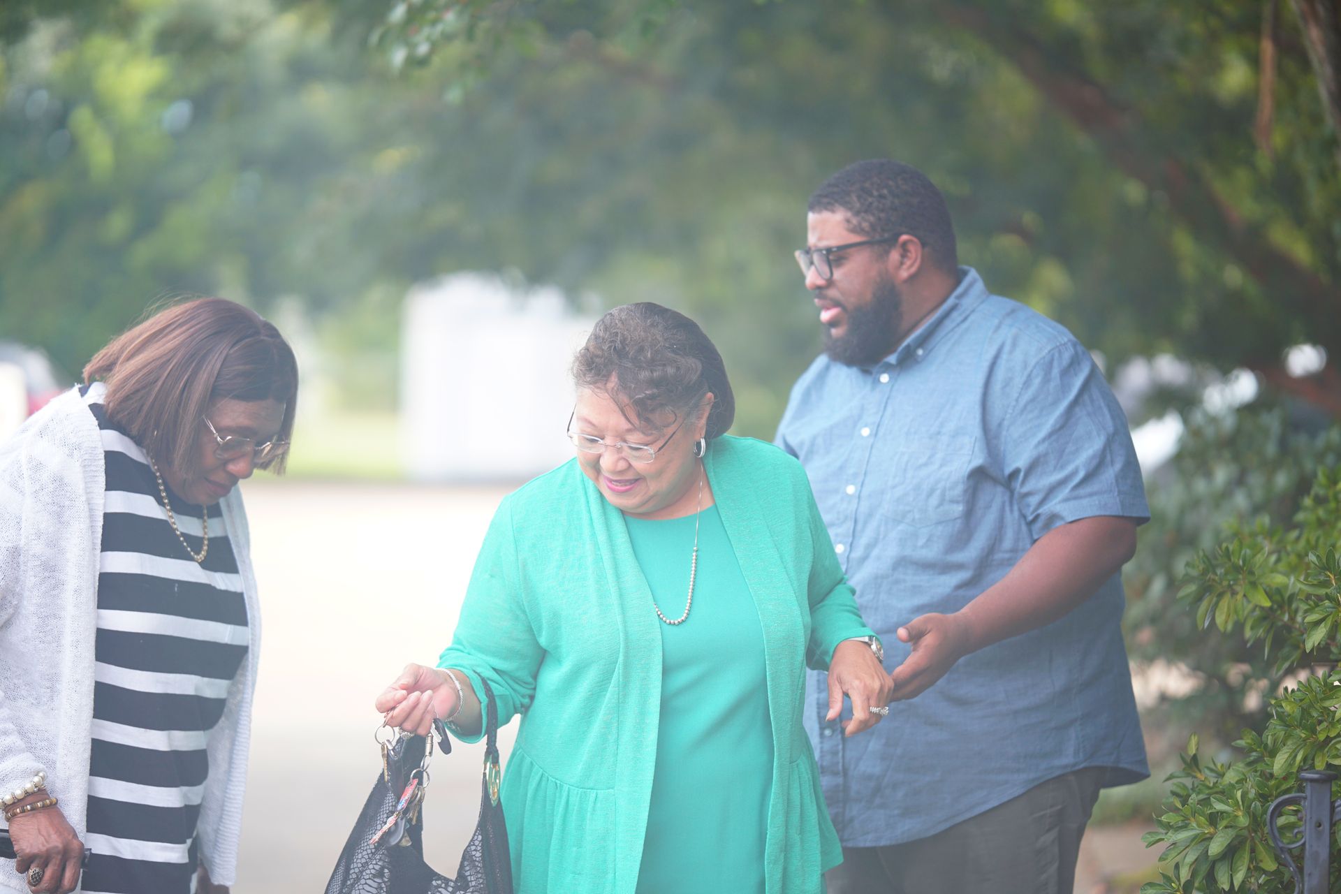 An African American male helping two African American women step up  a curb. 
