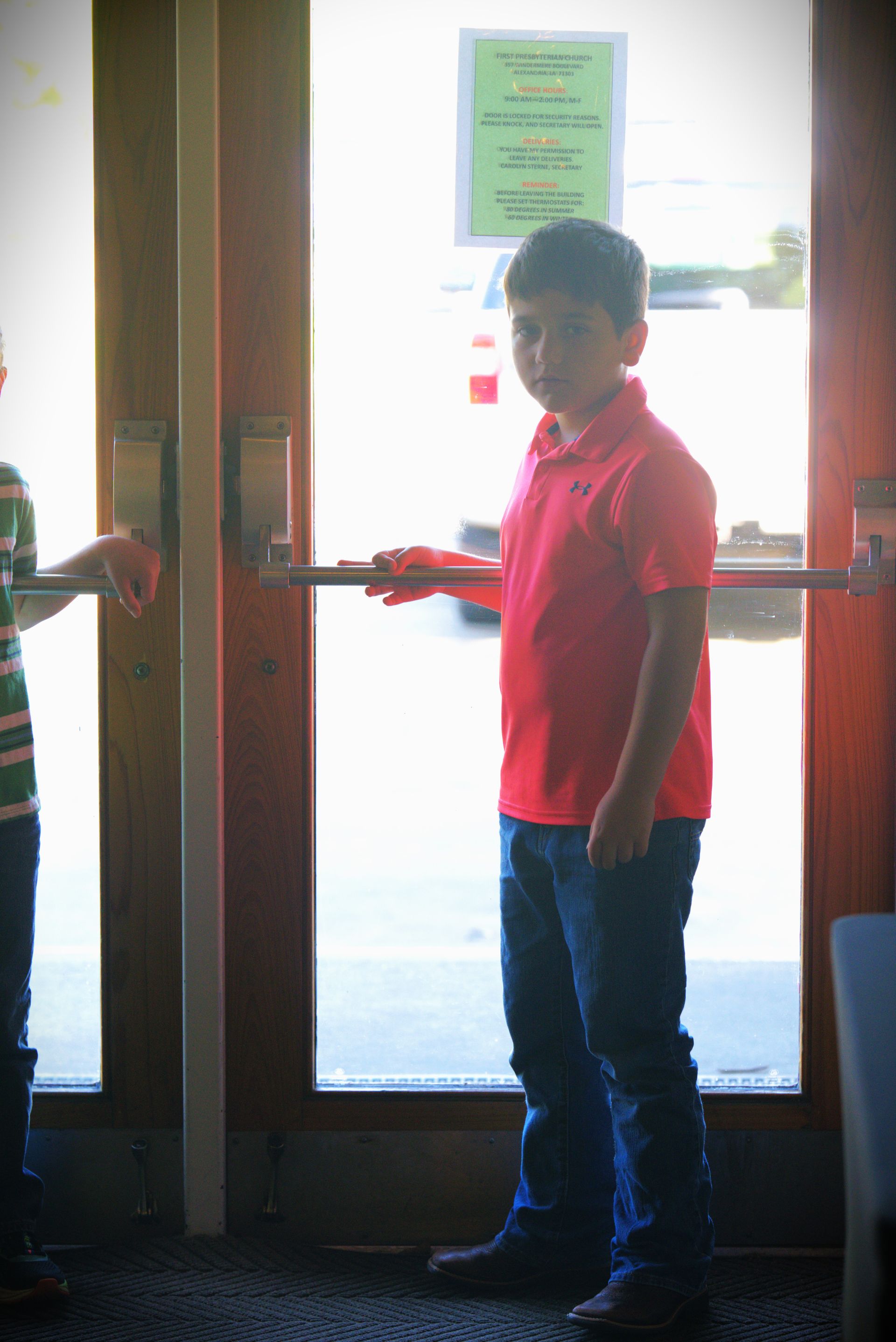 Young white male standing and waiting to open a door for church attendees. 