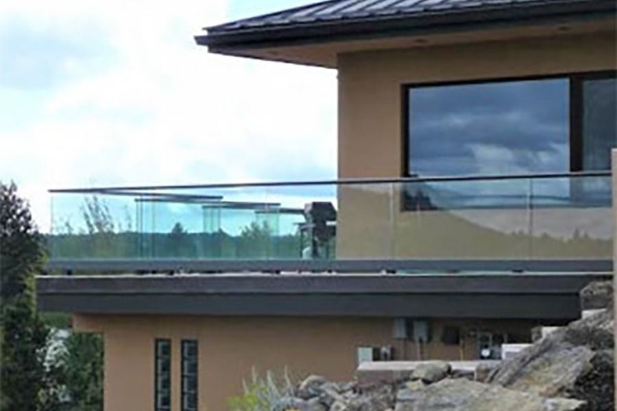 Modern house exterior with glass balcony and rocky landscaping