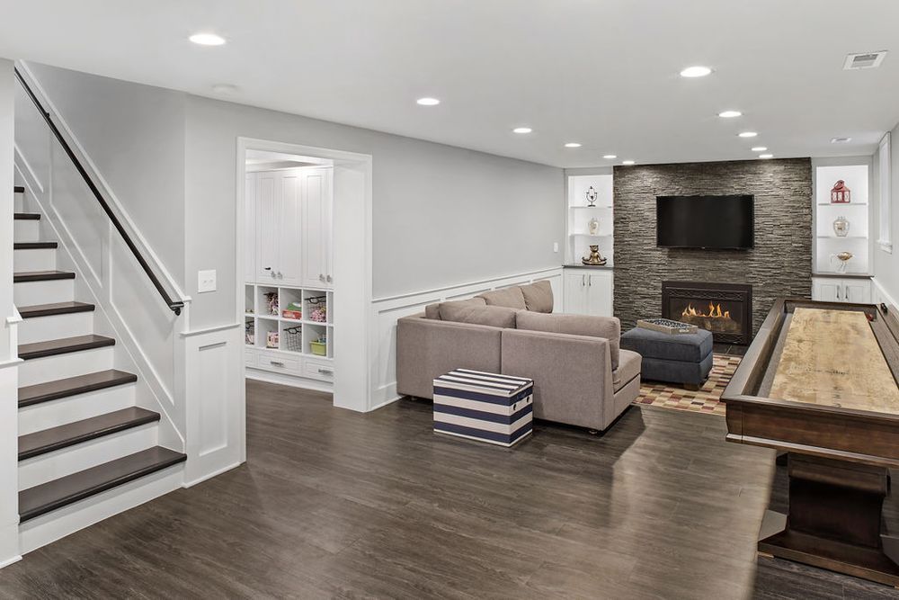 Finished basement with dark wood floor, fireplace, and shuffleboard table.