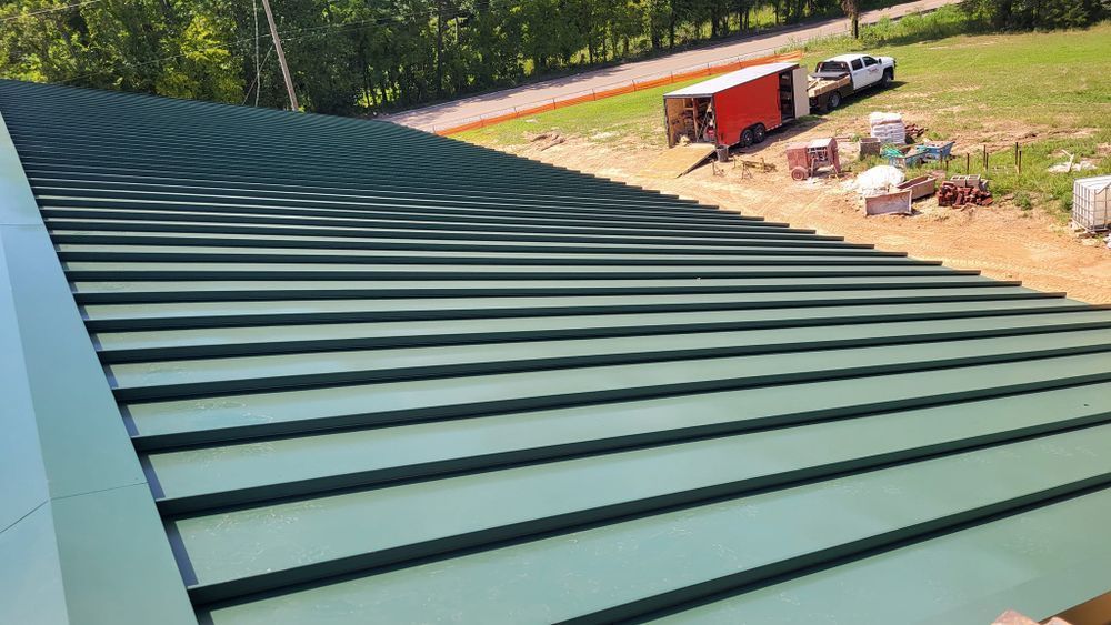 Green metal roof with linear grooves, construction site visible in background.