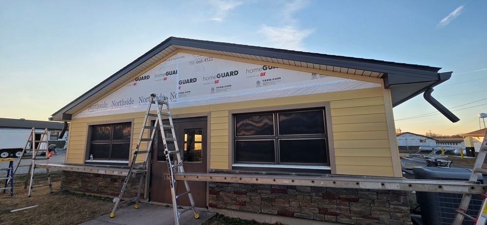 House under construction with yellow siding, windows, and ladder.