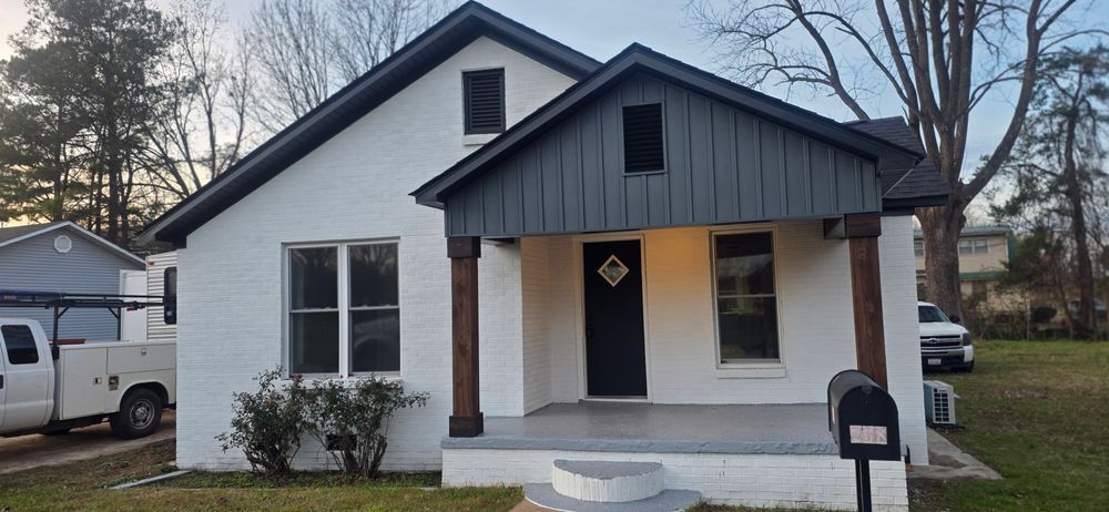 White brick house with dark gray trim and brown porch columns.