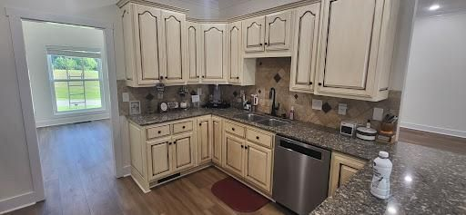 Kitchen with cream cabinets, granite countertops, stainless steel appliances, and a view of a window.