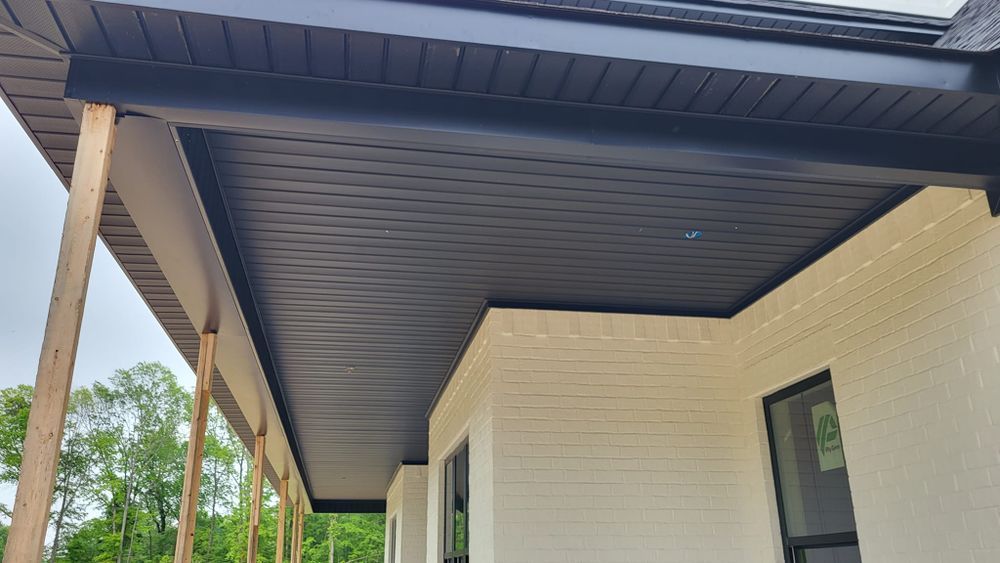 Black soffit and trim installed on a white brick home's porch.