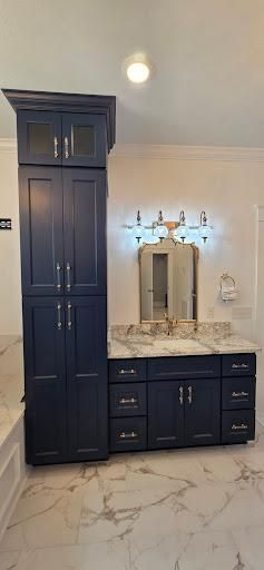 A navy blue bathroom vanity with granite countertop, mirror, and tall cabinet.
