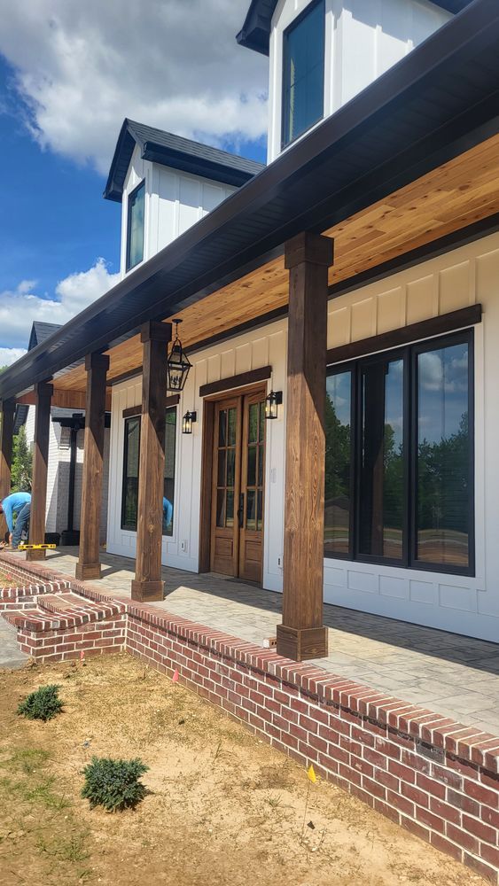 Farmhouse exterior with white siding, dark trim, and a brick porch.