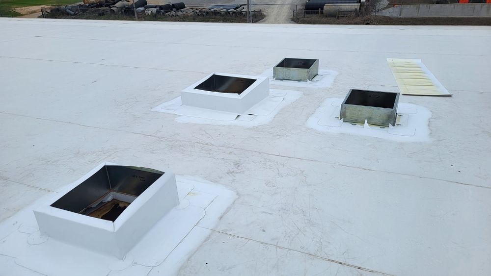 White commercial roof with four vents and a yellow panel.