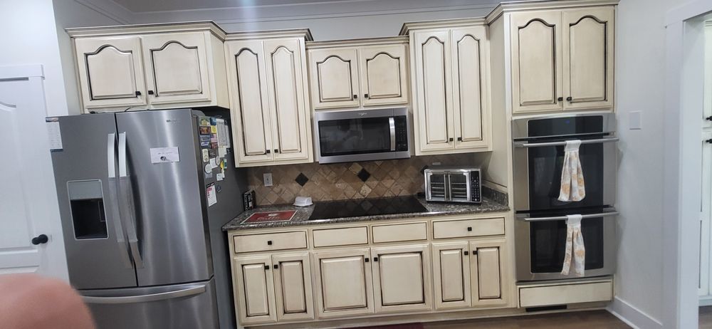 A kitchen with cream-colored cabinets, stainless steel appliances, and a microwave.
