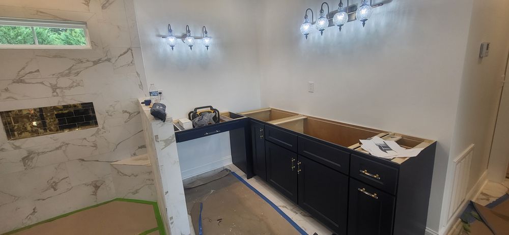 Bathroom renovation: black cabinets, marble tile shower, white walls, and a window.