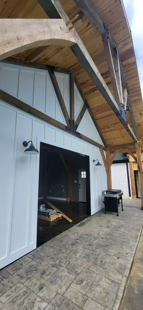Exterior of a building with white walls, dark wooden beams and a textured stone walkway.