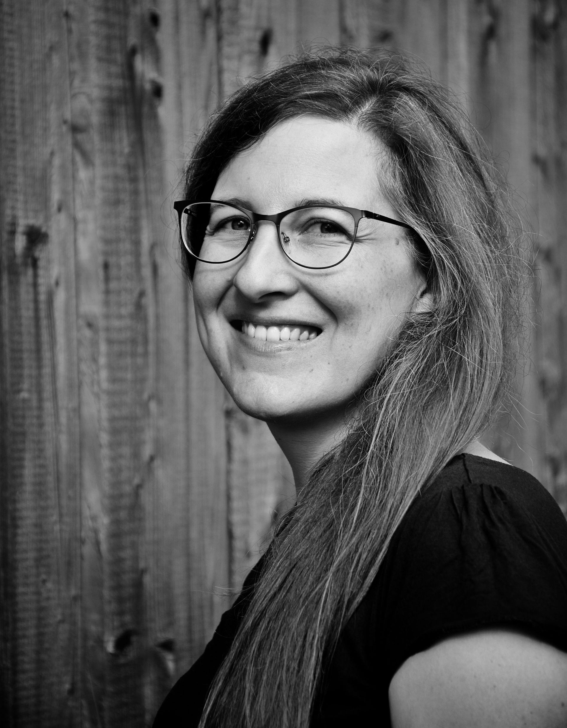Auf einem Schwarzweißfoto lächelt eine Frau mit Brille.