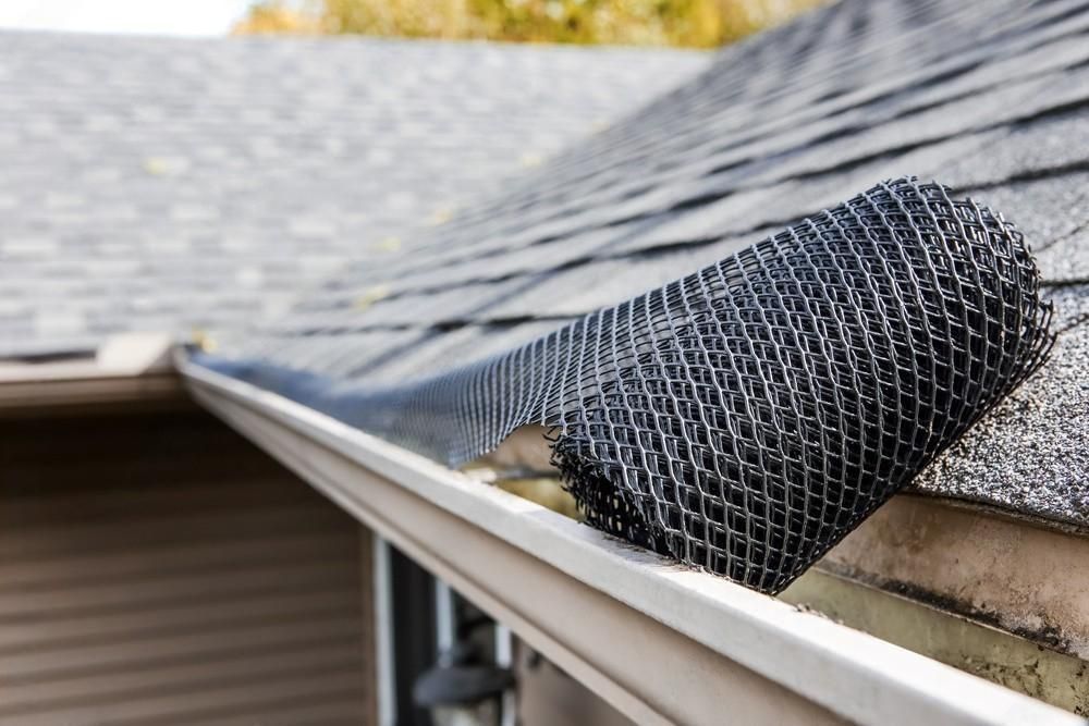 A man is fixing a gutter on the side of a house.