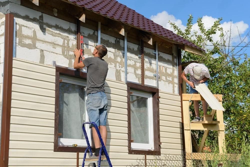 Two construction workers are working on the roof of a building.