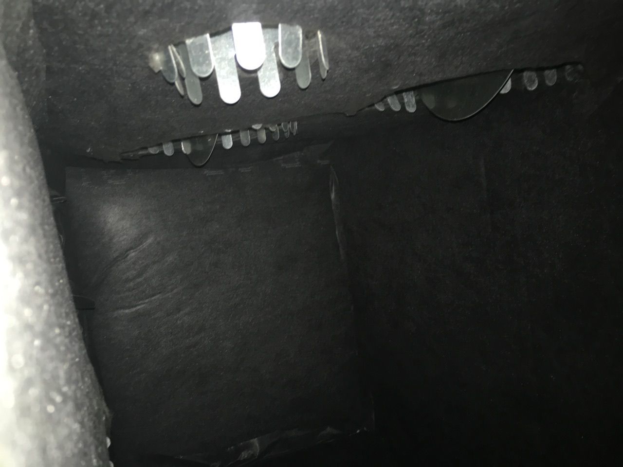 Dark interior, possibly a vent, showing a series of metal, slotted plates.