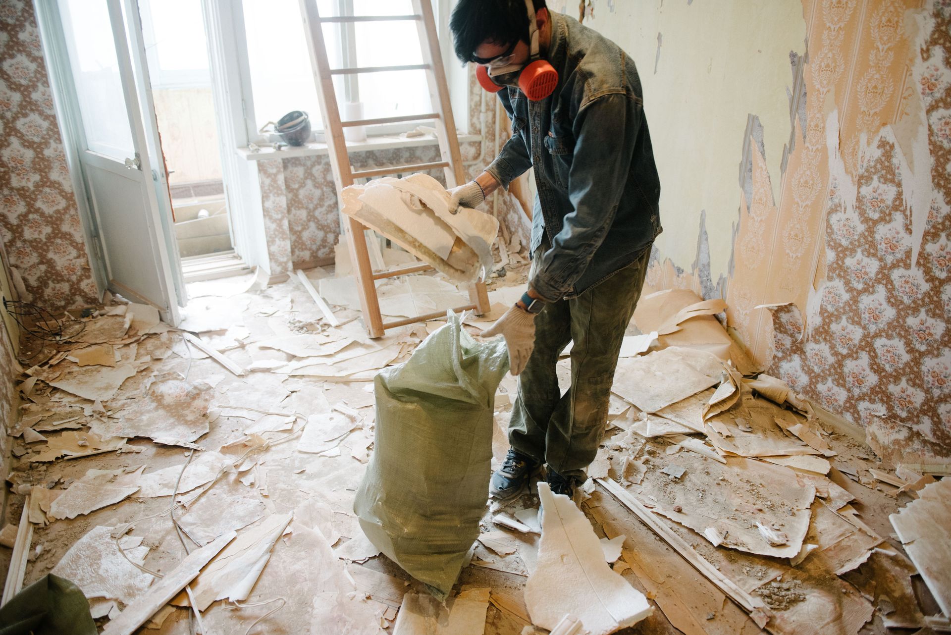 Worker cleans the renovation trash in an apartment in a bag.