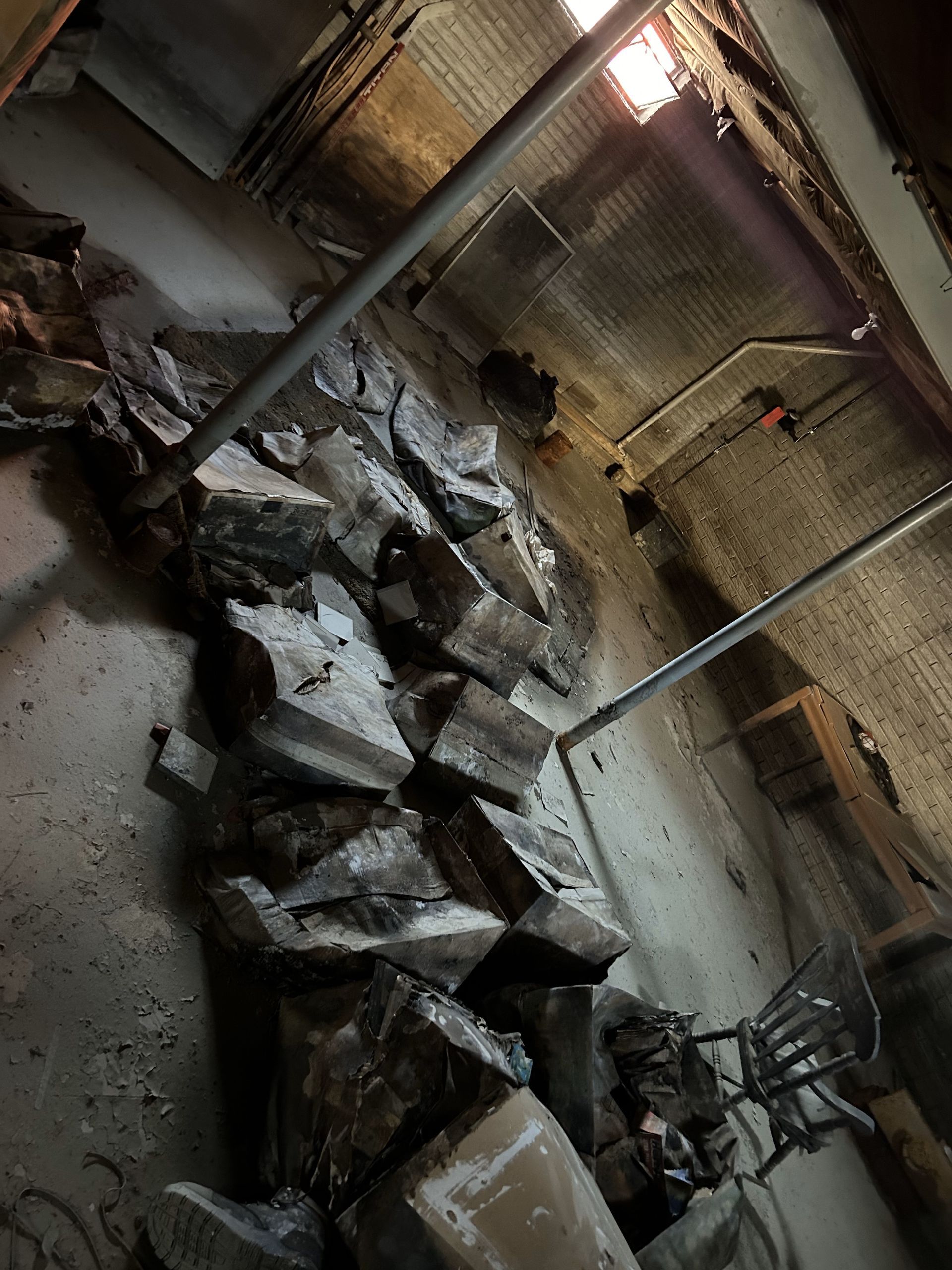 Damaged room with collapsed ceiling debris and broken concrete slabs scattered across the floor.
