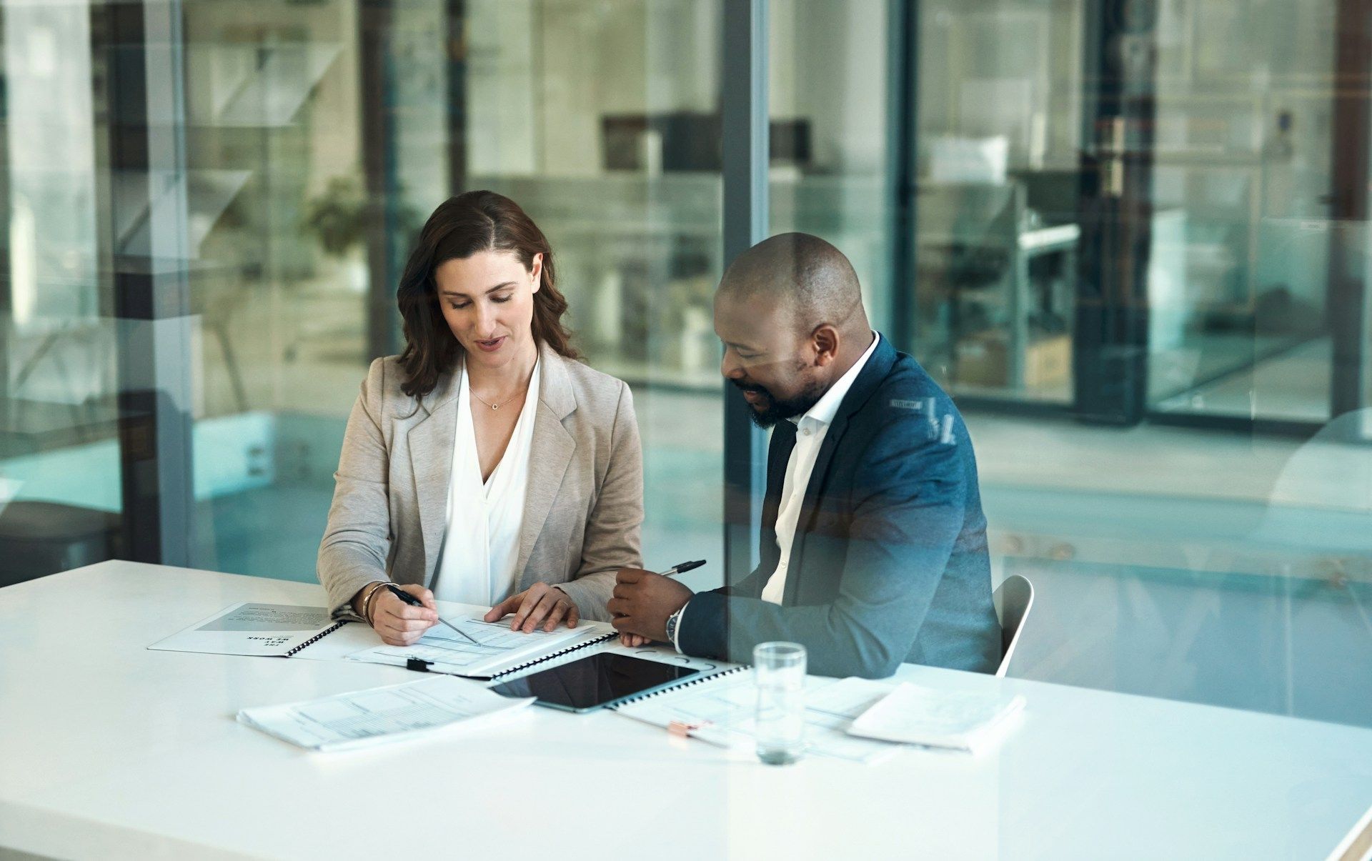 Woman and man in business attire reviewing documents at a table in an office.