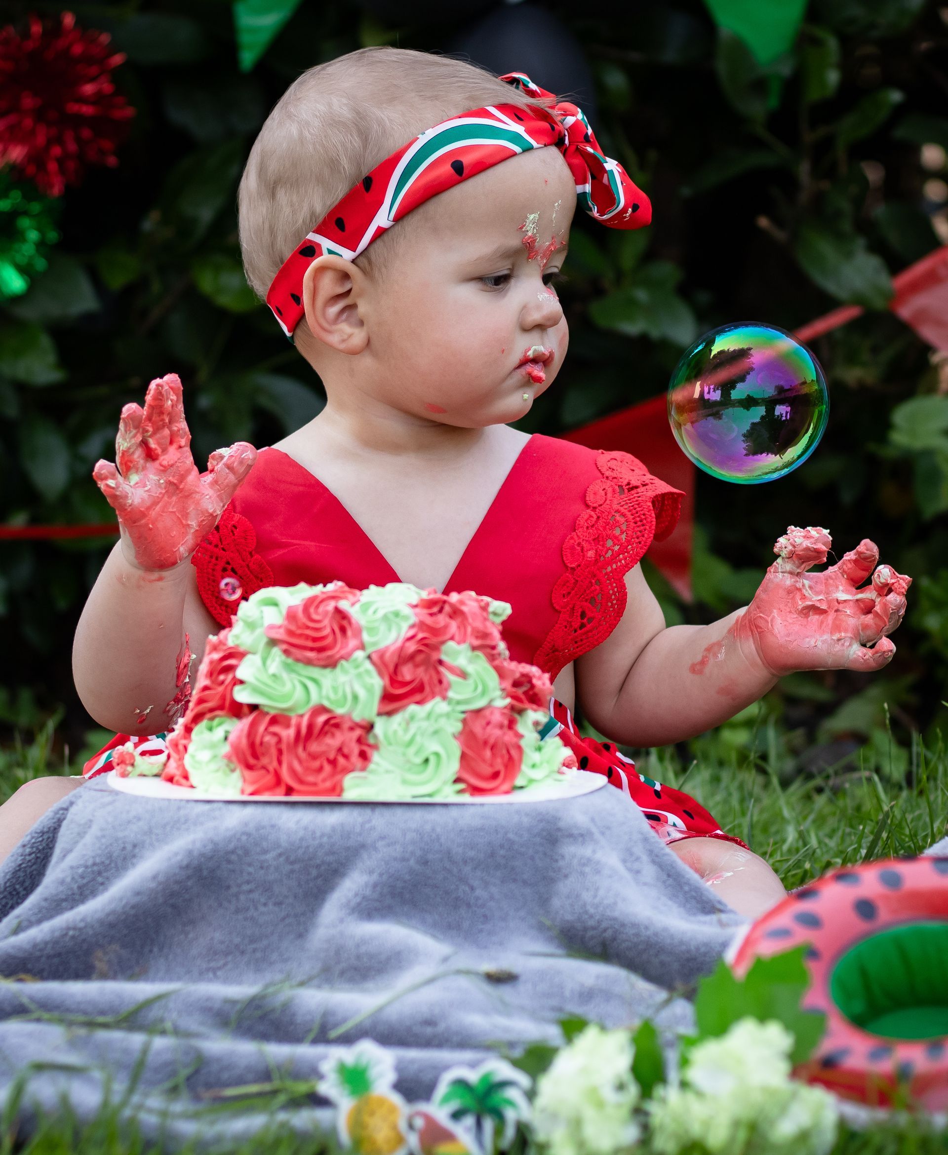 Baby in rood pakje met taart en bellenblaas.