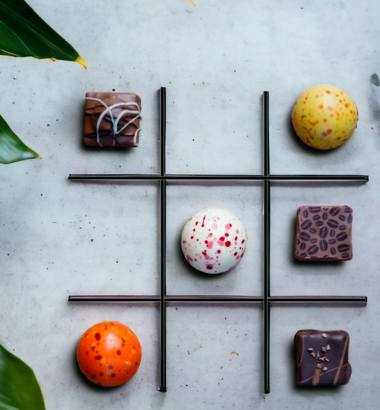 Een boter-kaas-en-eieren-bord gemaakt van chocoladesnoepjes op een grijze ondergrond met groene bladeren.