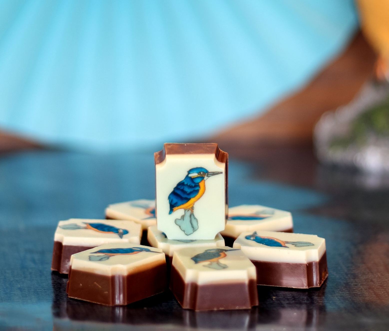 Chocoladesnoepjes met een vogelmotief, gerangschikt op een donkere ondergrond met een wazige blauwe achtergrond.