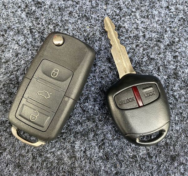 A person is holding a car key in front of a car