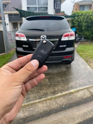 A person is holding a car key in front of a van that says domestic & commercial electrical services