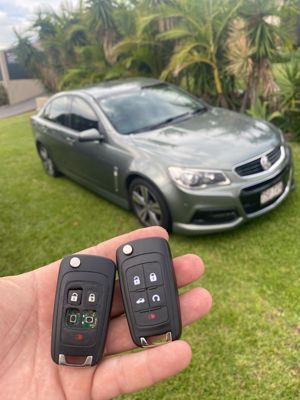 A person is holding a car key in front of a van that says domestic & commercial electrical services