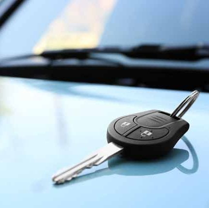 A car key is sitting on the hood of a car.