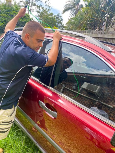 A man is opening the door of a red car