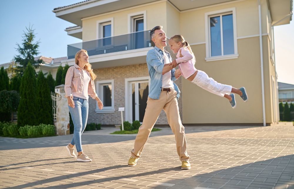A family is walking in front of their new house.