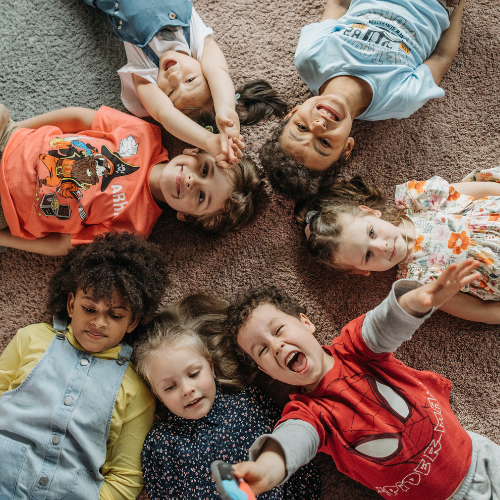 a group of children are laying on the floor in a circle .