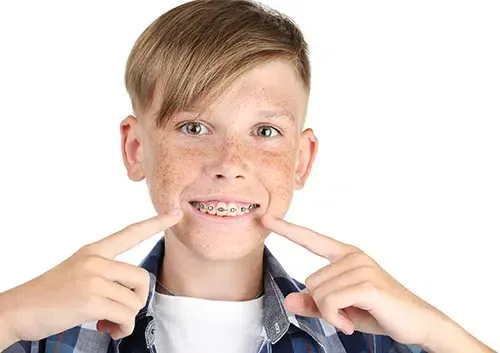 A young boy with braces on his teeth is making a funny face.
